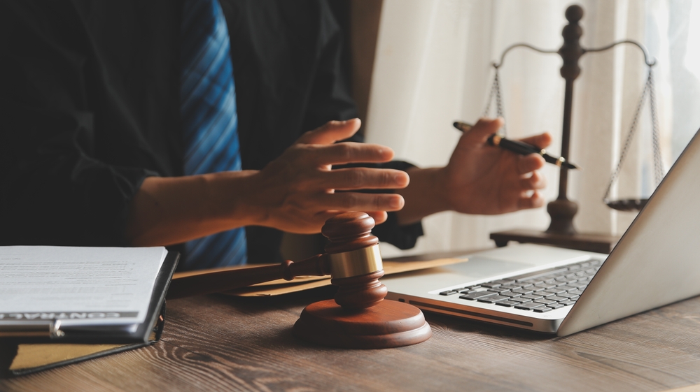 Business professionals and lawyers discussing contract documents with a brass scale on the desk in an office.